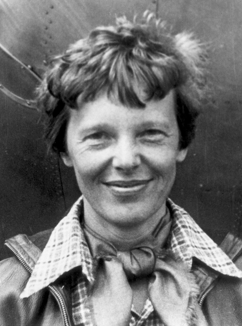 Amelia Earhart standing beneath an aircraft